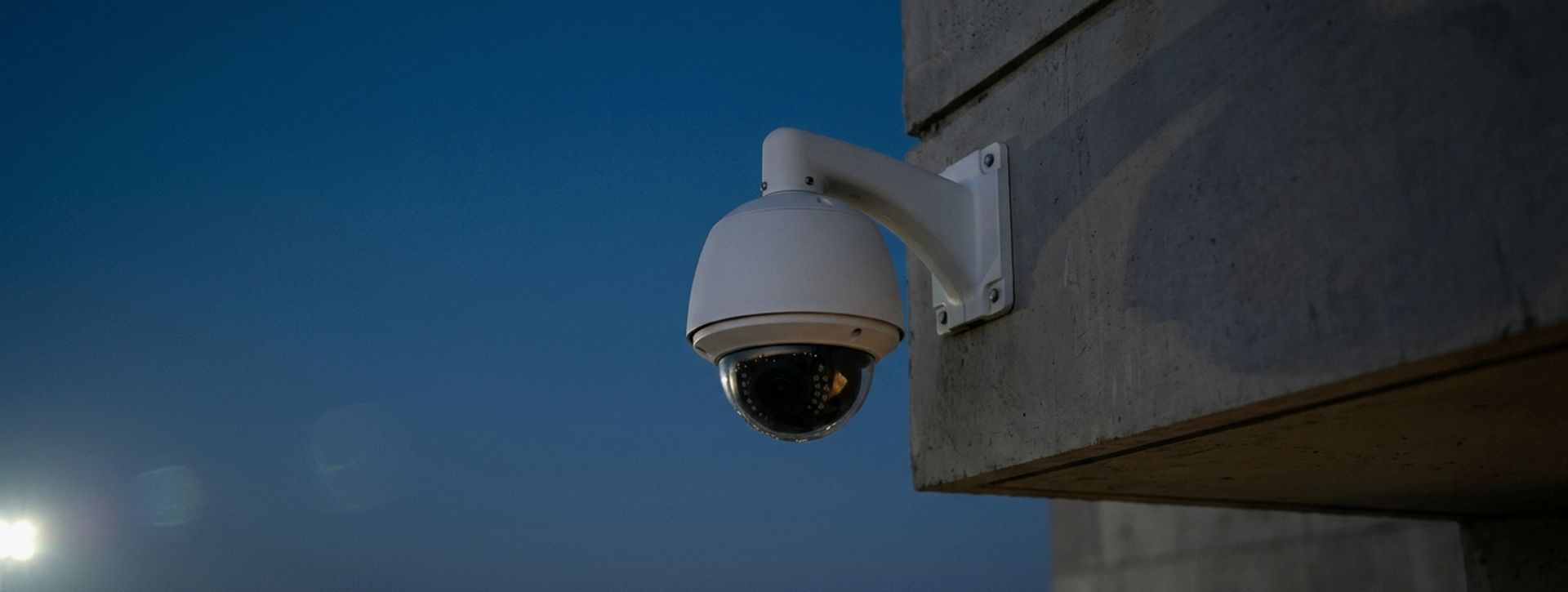 Dome CCTV camera on a building corner at dusk